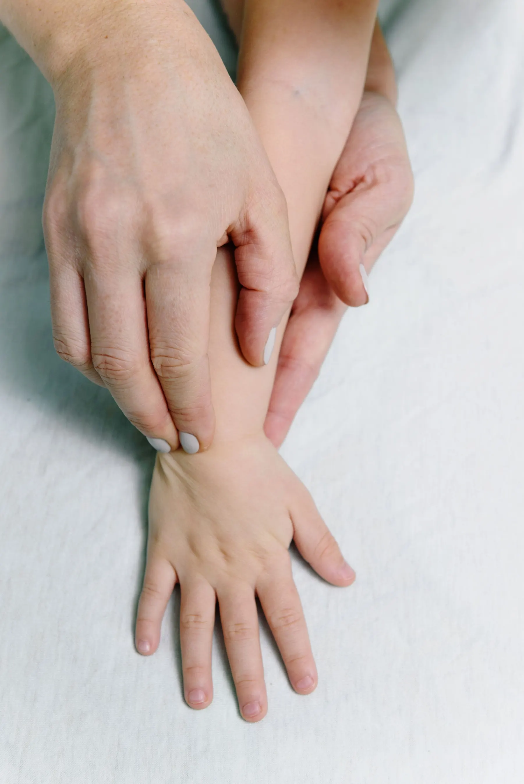An adult gently massaging a child's hand